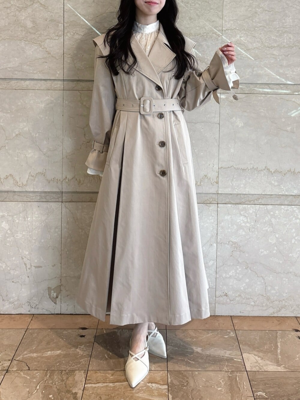 ホワイト系のパンプス、ベージュ系のトレンチコートを着用したレディースの冬コーディネートの2枚目の写真