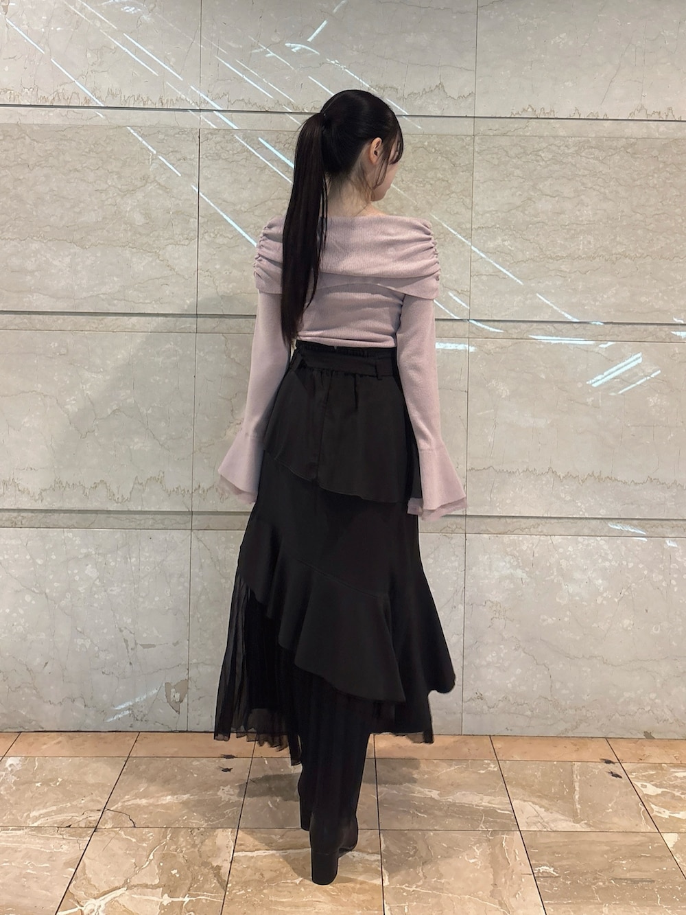 ブラック系のスカート、ピンク系のニット/セーター、ブラック系のブーツを着用したレディースの冬コーディネートの6枚目の写真