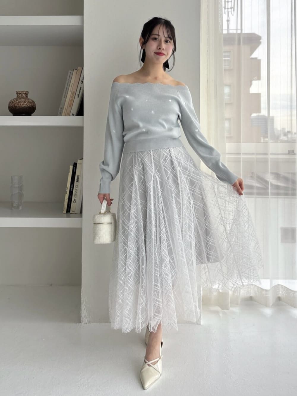 ホワイト系のパンプス、グリーン系のニット/セーター、グレー系のスカートを着用したレディースの冬コーディネートの3枚目の写真