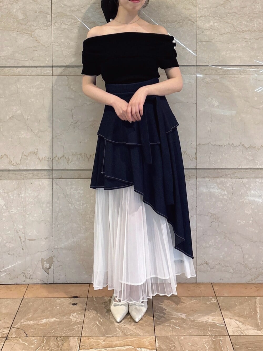 ホワイト系のパンプス、ブルー系のスカート、ブラック系のニット/セーターを着用したレディースの春コーディネートの6枚目の写真