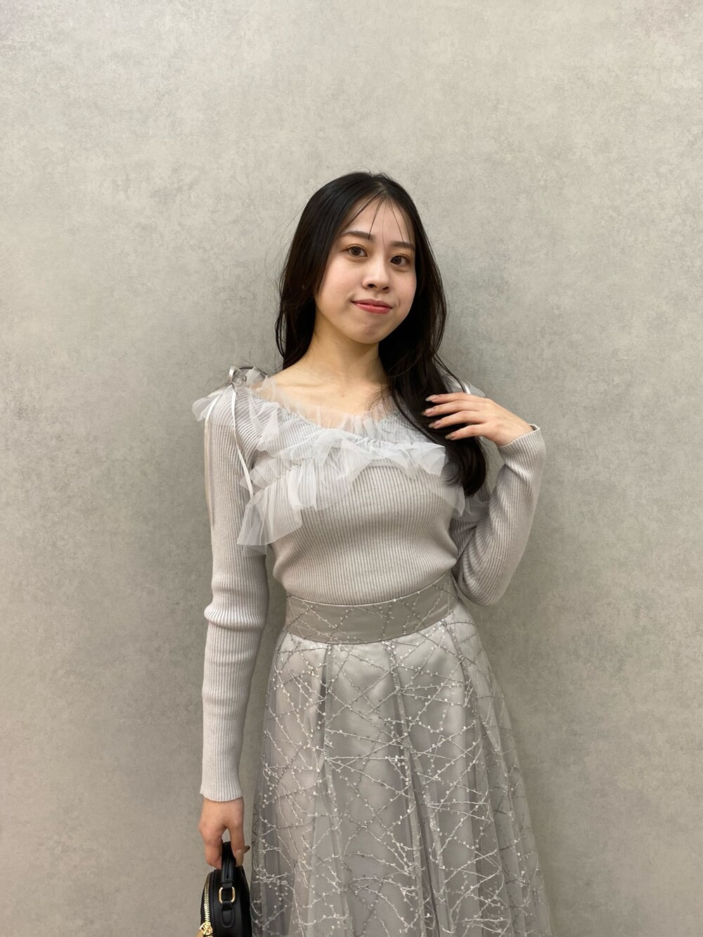 グレー系のニット/セーター、グレー系のスカートを着用したレディースの秋コーディネートの6枚目の写真