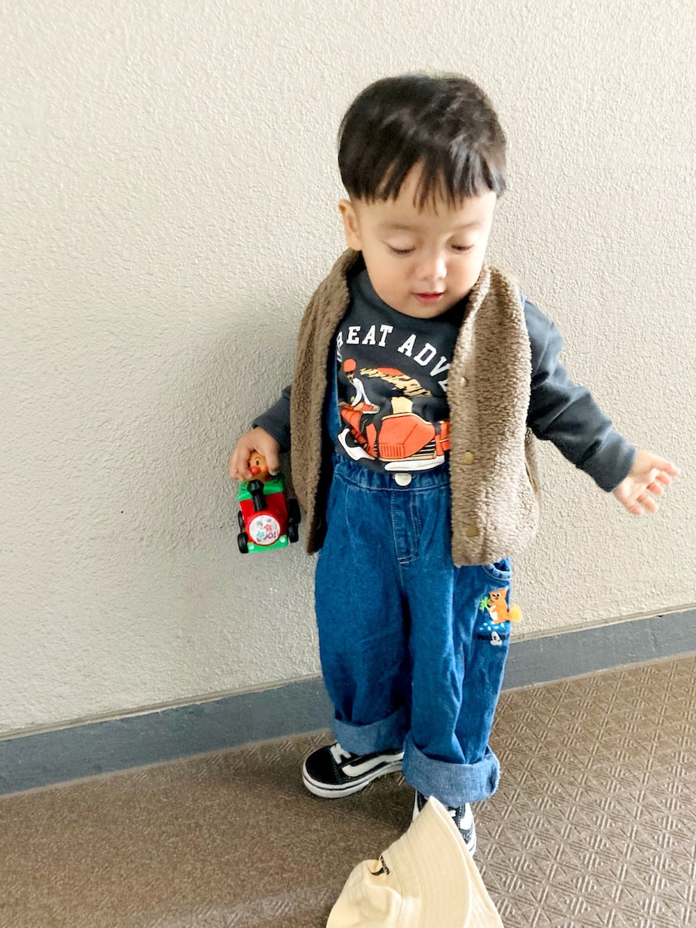 ブラウン系のベスト、ブラック系のスニーカー、グレー系のスウェットを着用したキッズの冬コーディネートの3枚目の写真