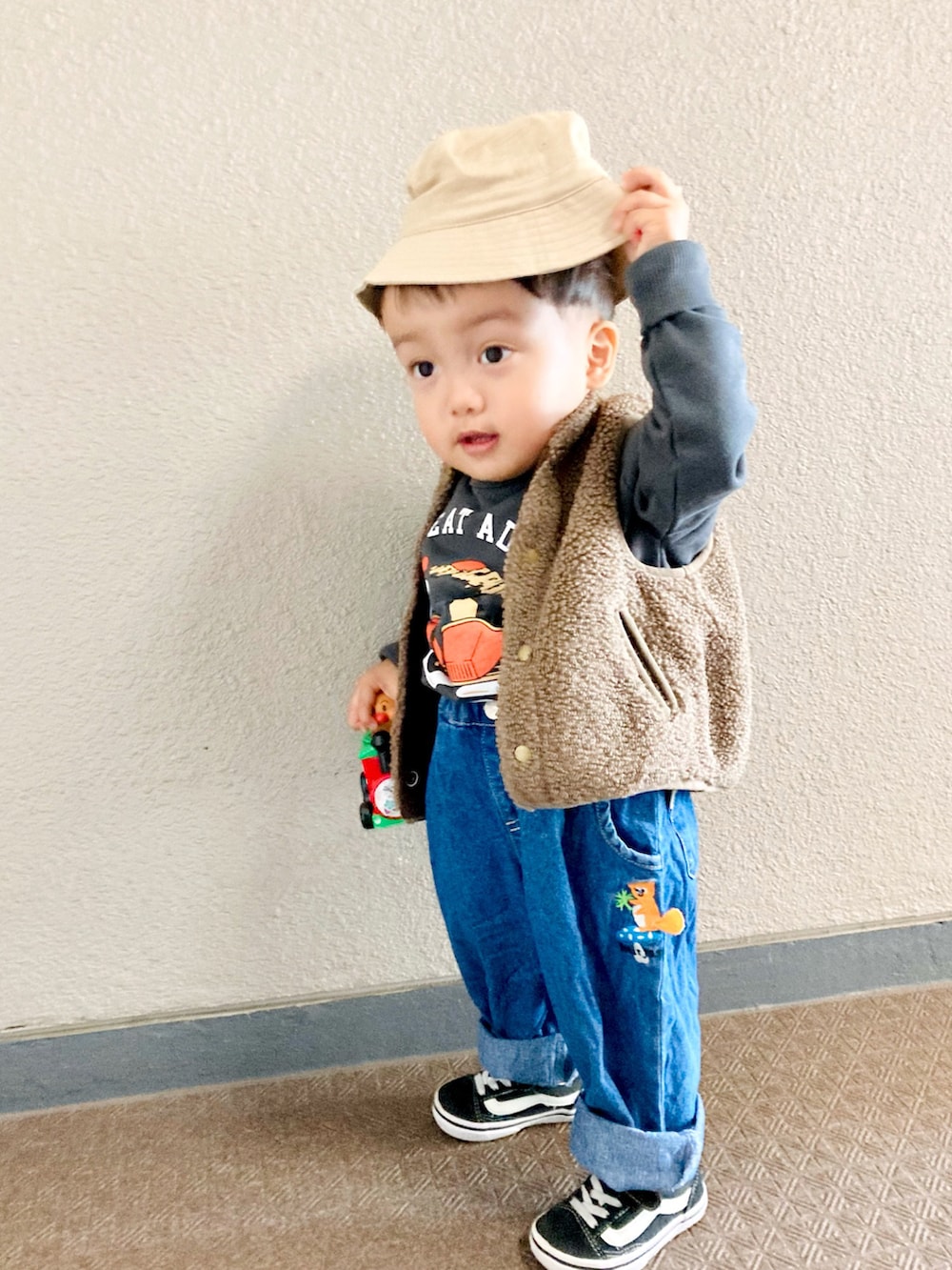 ブラウン系のベスト、ブラック系のスニーカー、グレー系のスウェットを着用したキッズの冬コーディネートの2枚目の写真