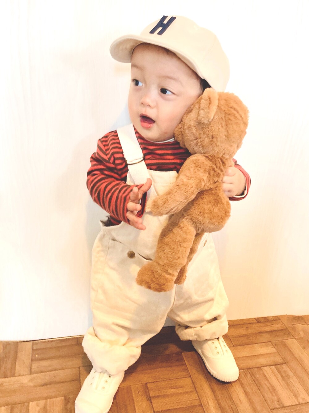 ホワイト系のオールインワン・サロペット、オレンジ系のTシャツ/カットソー、ホワイト系のスリッポンを着用したキッズの春コーディネートの2枚目の写真