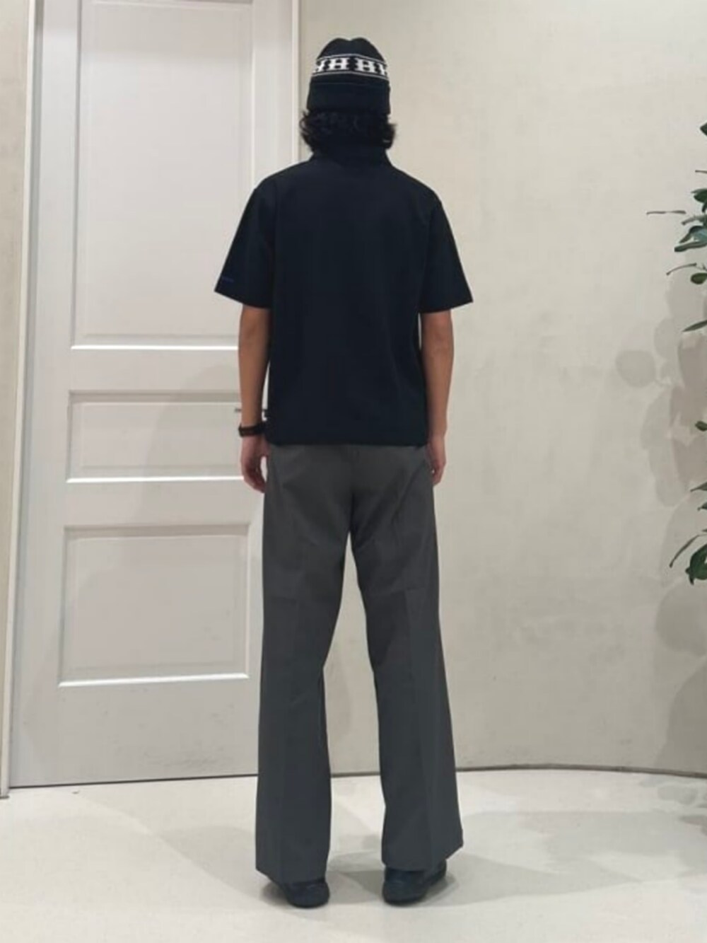 グレー系のスラックス、ブラック系のポロシャツを着用したメンズの夏コーディネートの2枚目の写真