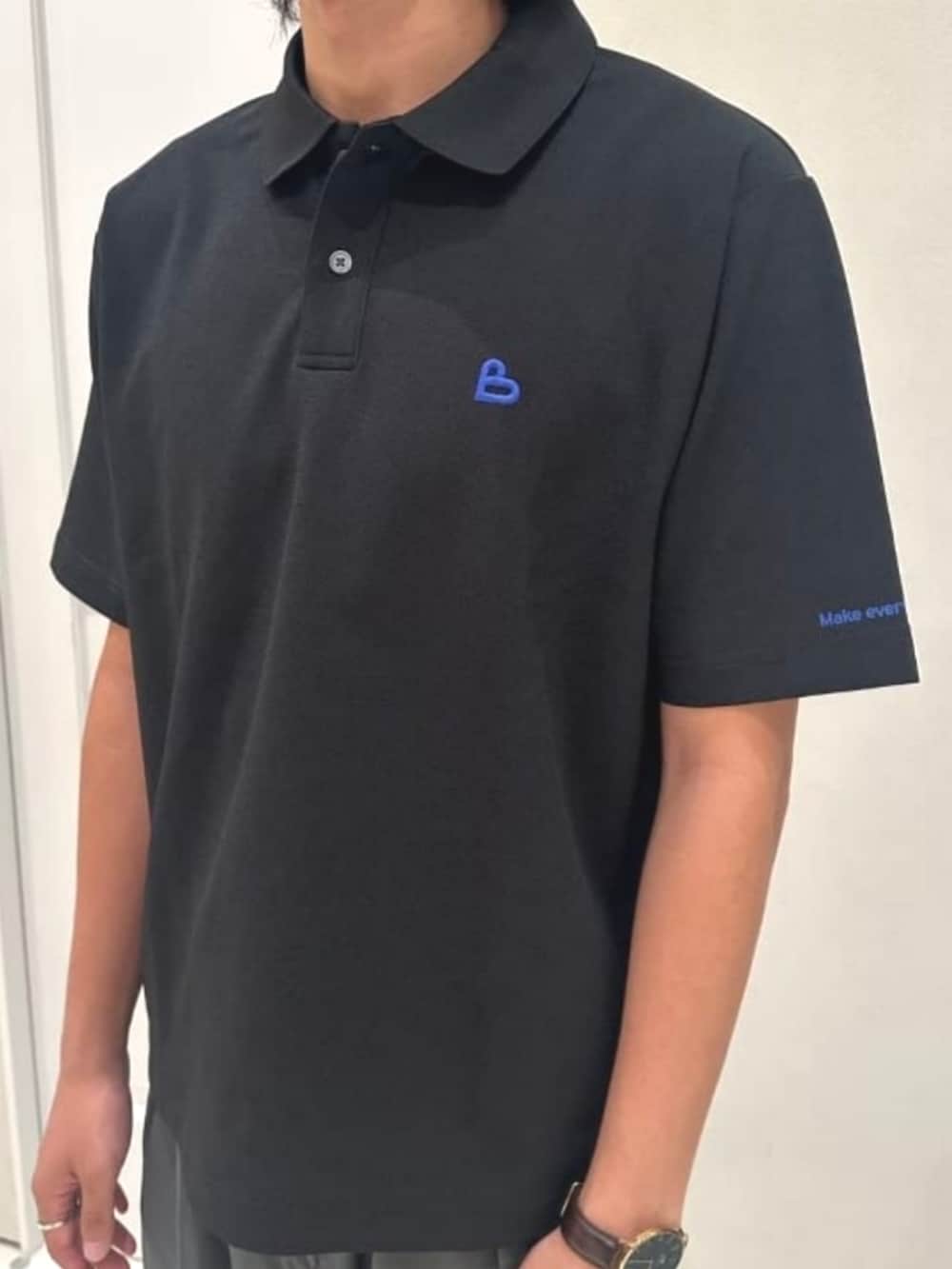 グレー系のスラックス、ブラック系のポロシャツを着用したメンズの夏コーディネートの3枚目の写真