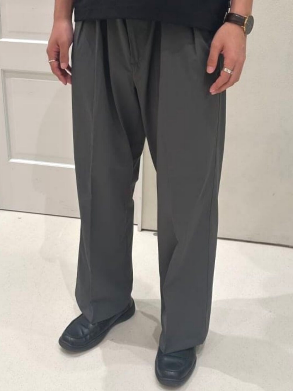 グレー系のスラックス、ブラック系のポロシャツを着用したメンズの夏コーディネートの4枚目の写真