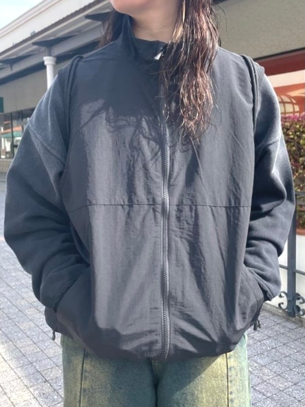 ブラック系のベスト、ブルー系のデニムパンツ、ブラック系のスウェットを着用したレディースの春コーディネートの4枚目の写真