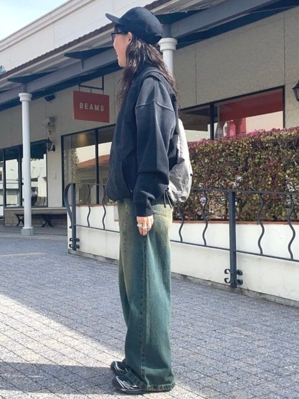 ブラック系のベスト、ブルー系のデニムパンツ、ブラック系のスウェットを着用したレディースの春コーディネートの3枚目の写真