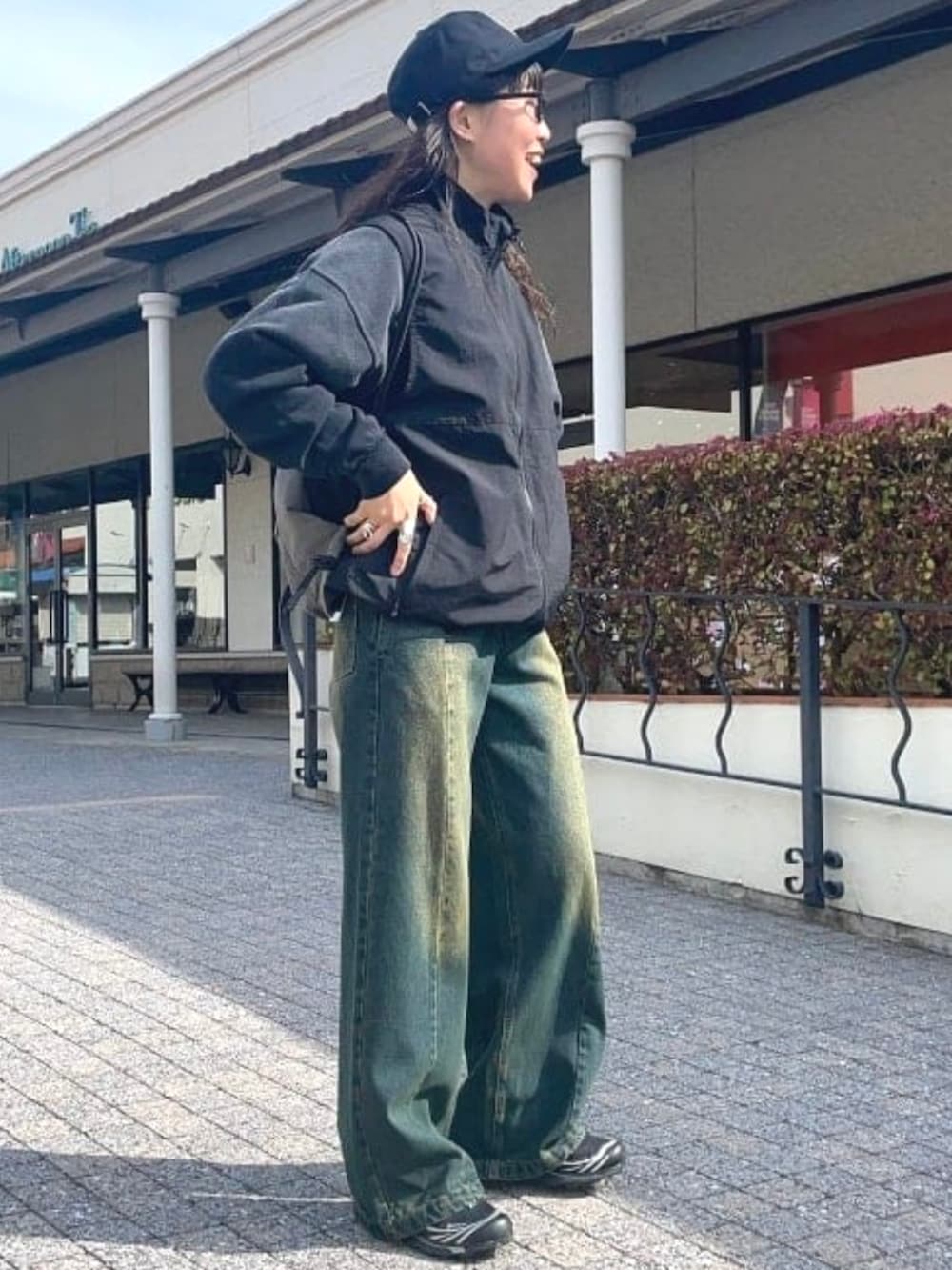 ブラック系のベスト、ブルー系のデニムパンツ、ブラック系のスウェットを着用したレディースの春コーディネートの2枚目の写真