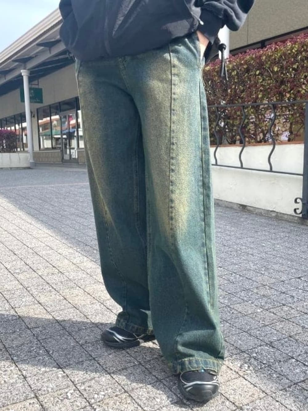 ブラック系のベスト、ブルー系のデニムパンツ、ブラック系のスウェットを着用したレディースの春コーディネートの5枚目の写真