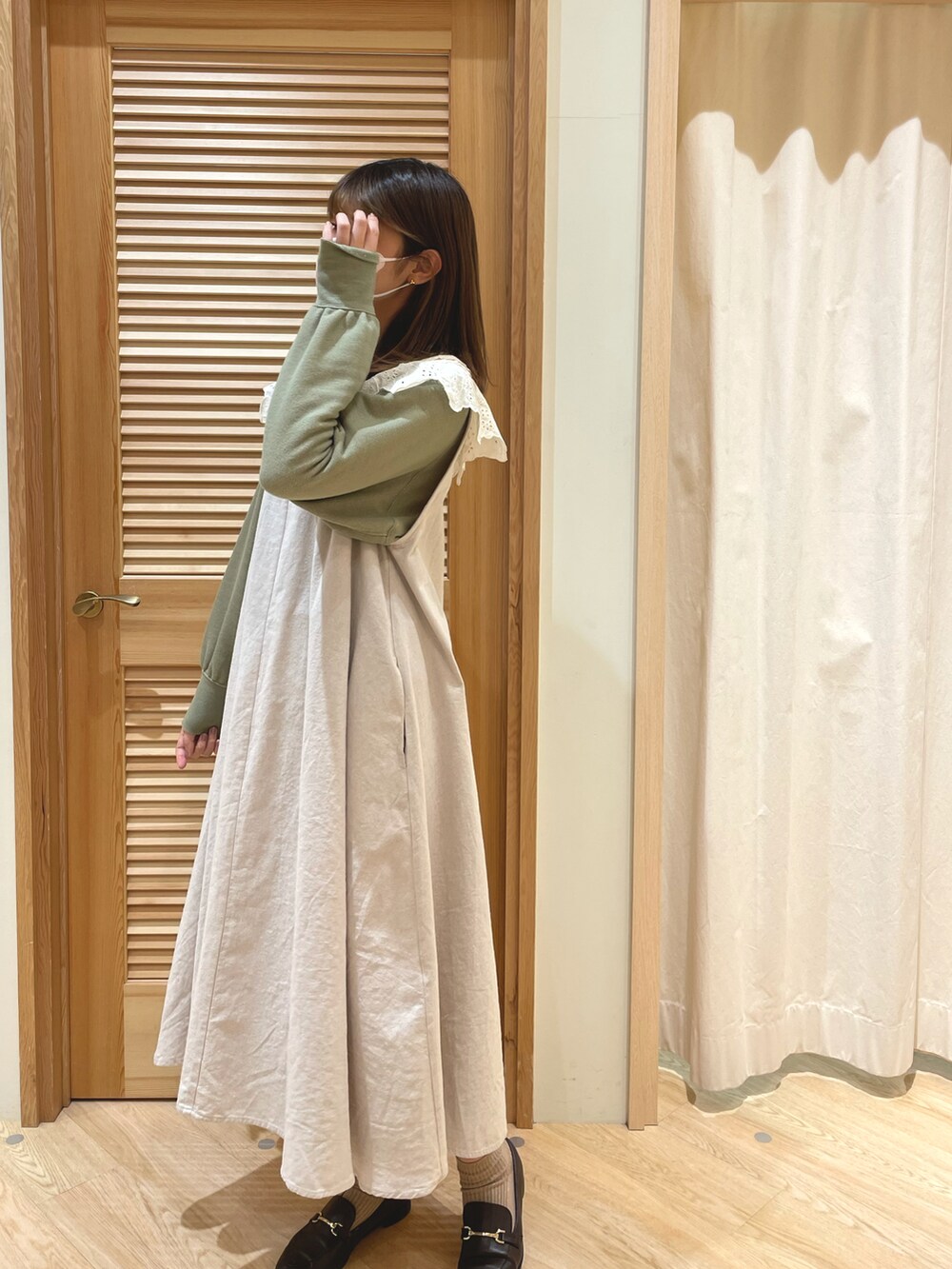 グリーン系のTシャツ/カットソー、ホワイト系のジャンパースカート、ホワイト系の付け襟を着用したレディースの冬コーディネートの2枚目の写真