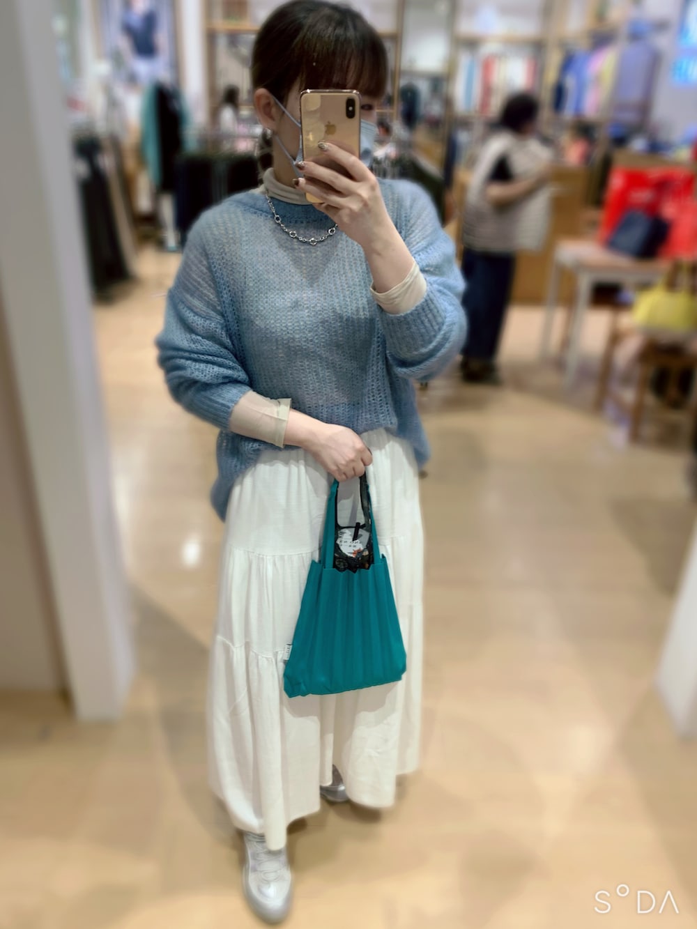 ブルー系のニット/セーター、ホワイト系のスカート、グリーン系のバッグを着用したレディースの春コーディネートの2枚目の写真