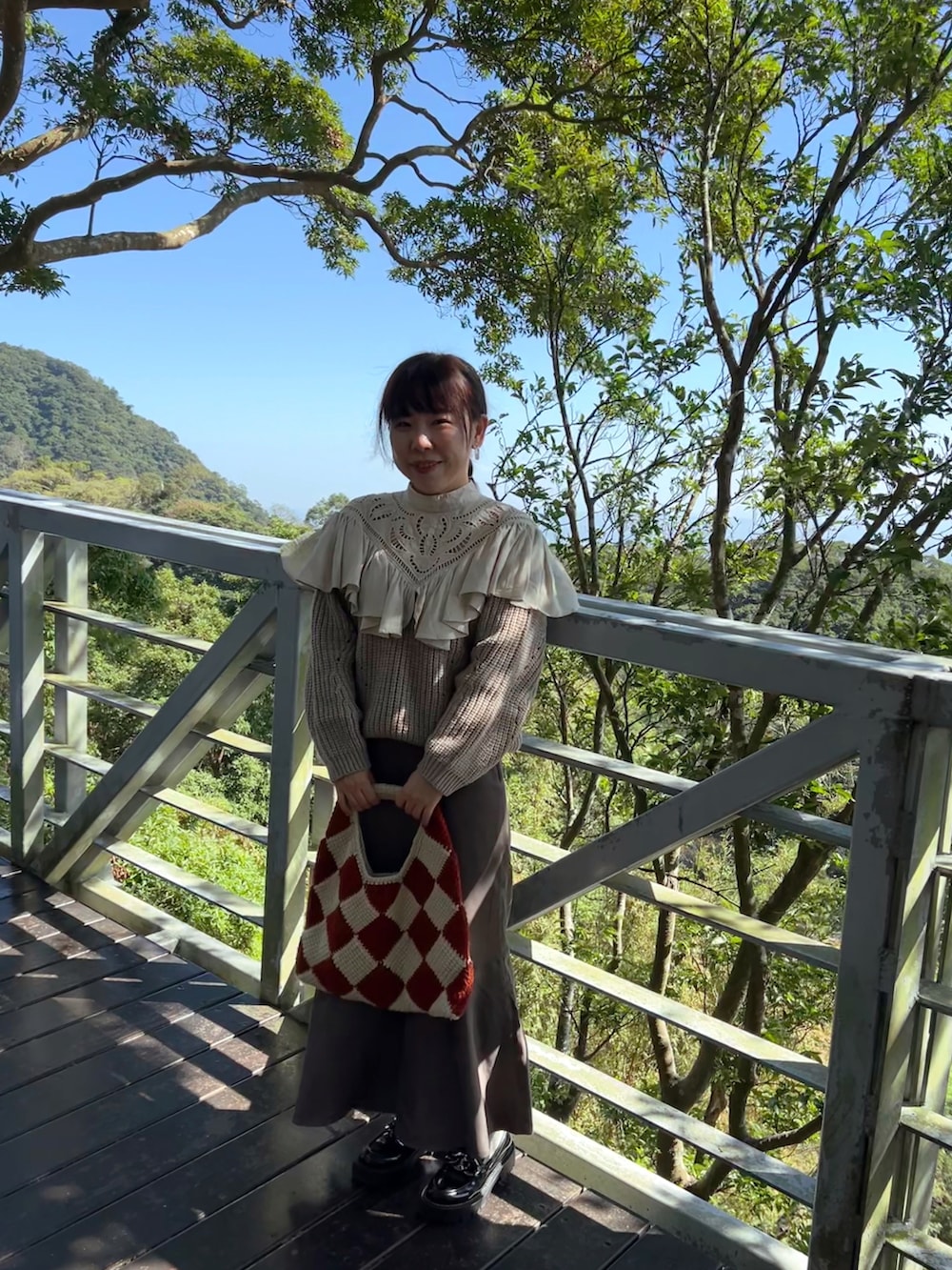 ベージュ系のニット/セーター、グレー系のスカート、ブラック系のシューズを着用したレディースの春コーディネートの2枚目の写真