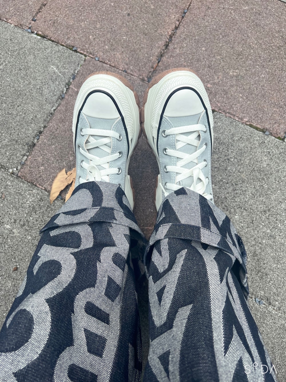 ブラック系のショルダーバッグ、ブルー系のスニーカー、ホワイト系のTシャツ/カットソーを着用したレディースの夏コーディネートの2枚目の写真