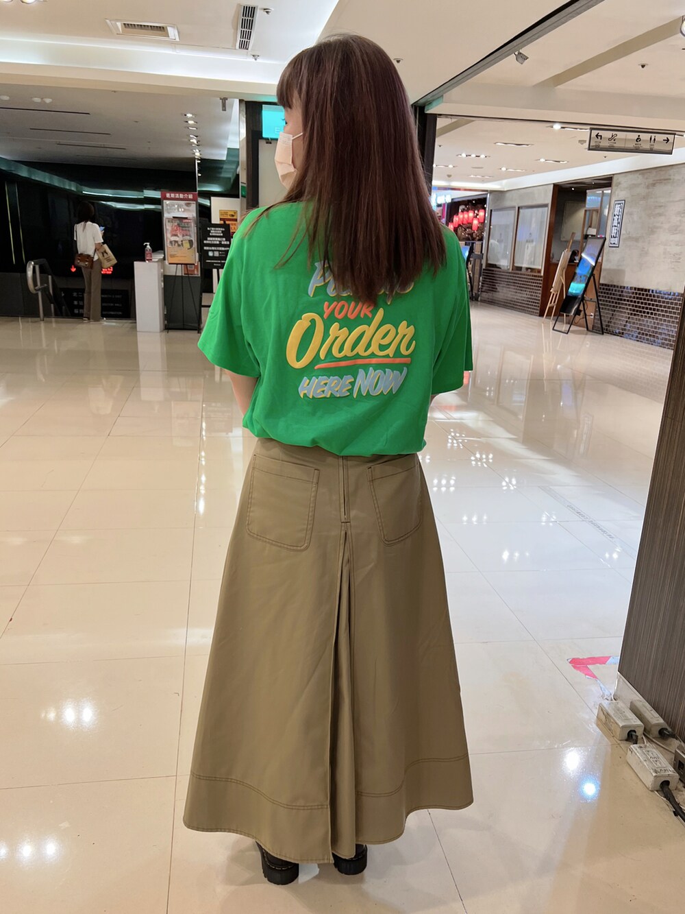 グリーン系のTシャツ/カットソー、ベージュ系のスカート、グリーン系のバッグを着用したレディースの夏コーディネートの2枚目の写真