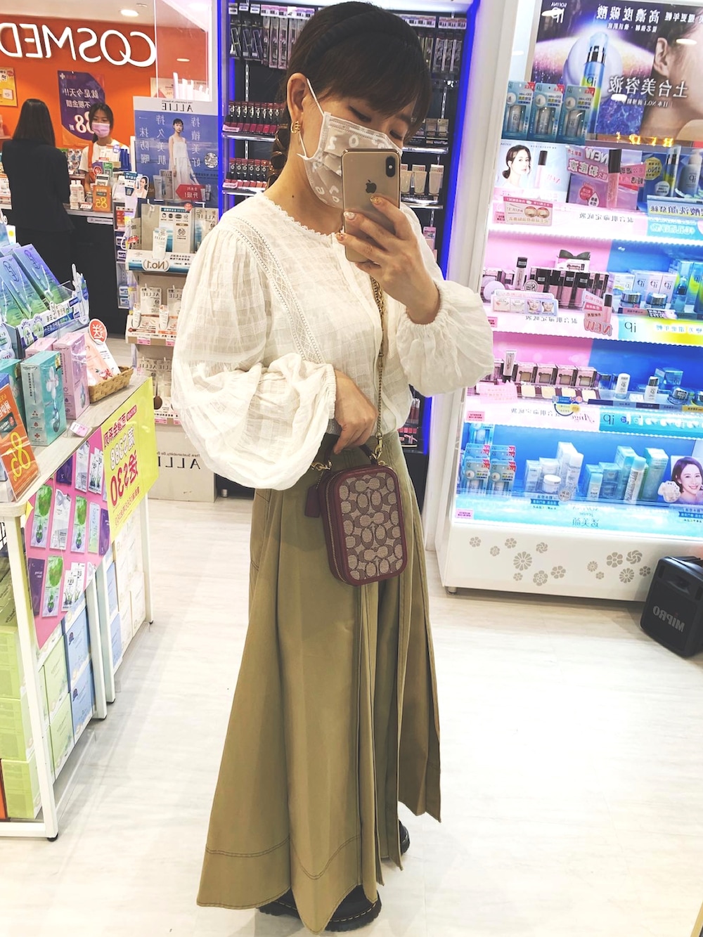 ベージュ系のスカート、ブラック系のローファー、ホワイト系のシャツ/ブラウスを着用したレディースの夏コーディネートの2枚目の写真