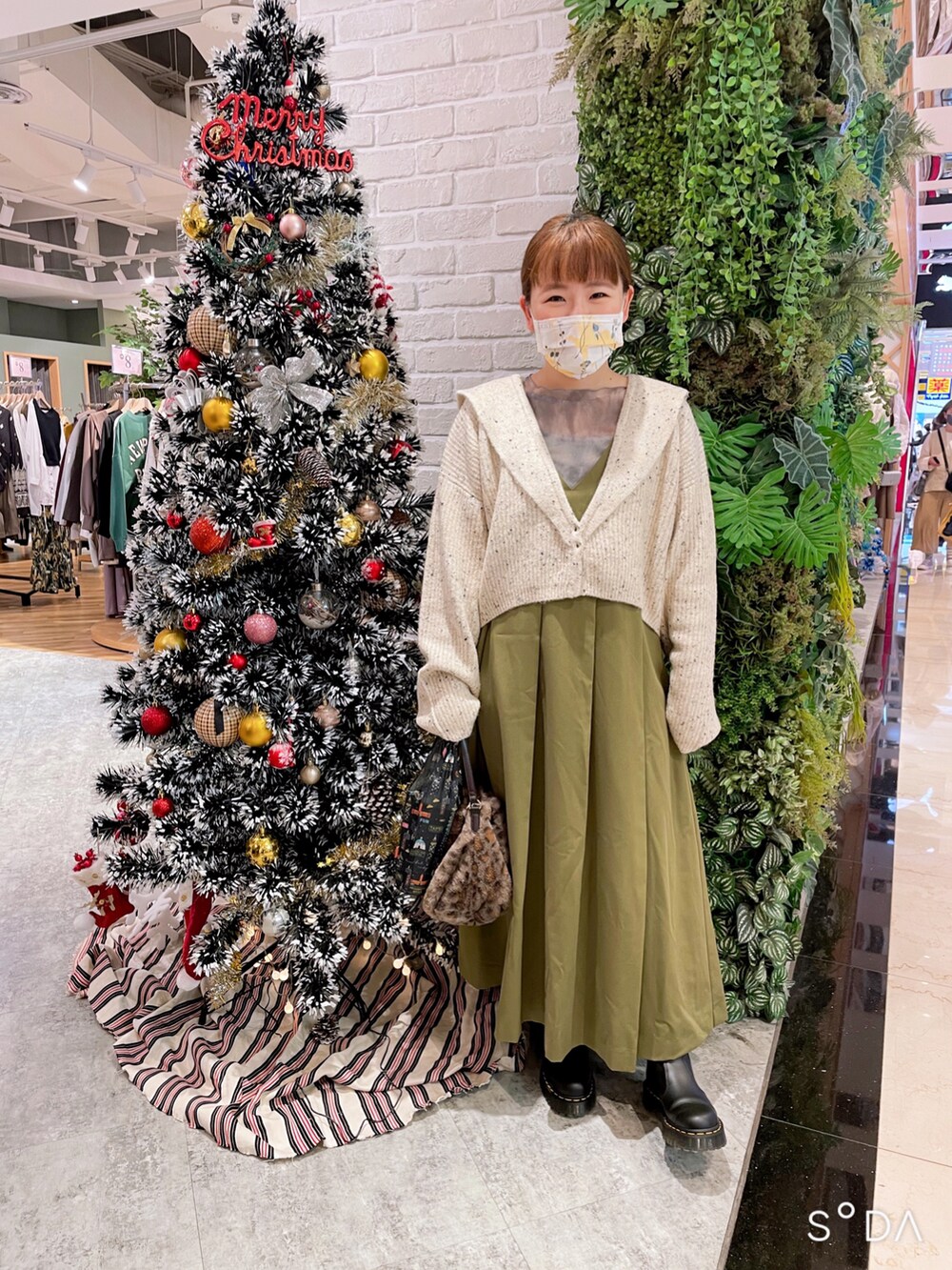 ベージュ系のショルダーバッグ、ホワイト系のカーディガン/ボレロ、グリーン系のワンピースを着用したレディースの秋コーディネートの2枚目の写真