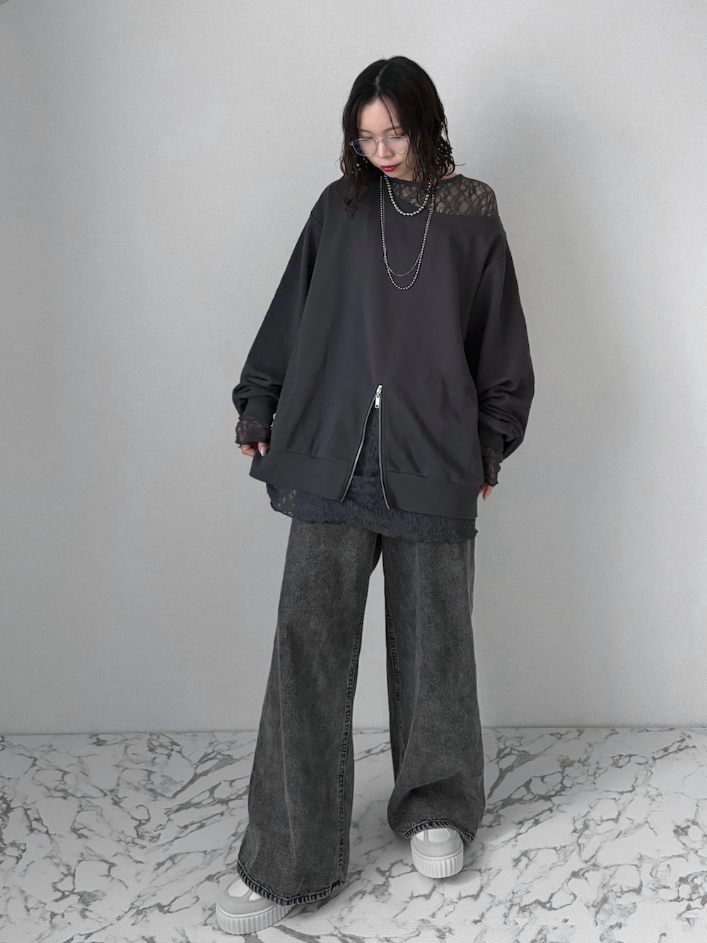 ブラック系のデニムパンツ、グレー系のスニーカー、ブラック系のトップスを着用したレディースの春コーディネートの4枚目の写真