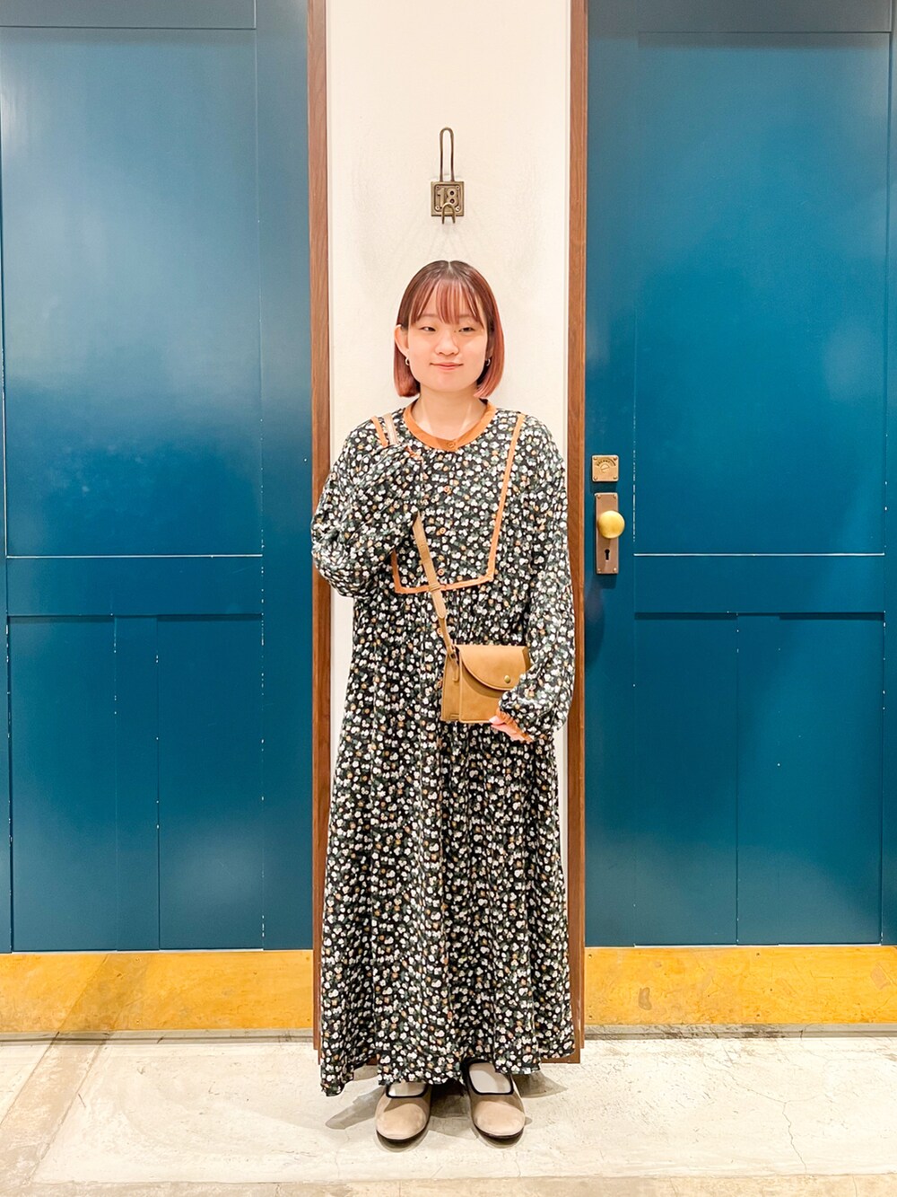 ブラウン系のベスト、グレー系のワンピース、ベージュ系のショルダーバッグを着用したレディースの秋コーディネートの2枚目の写真