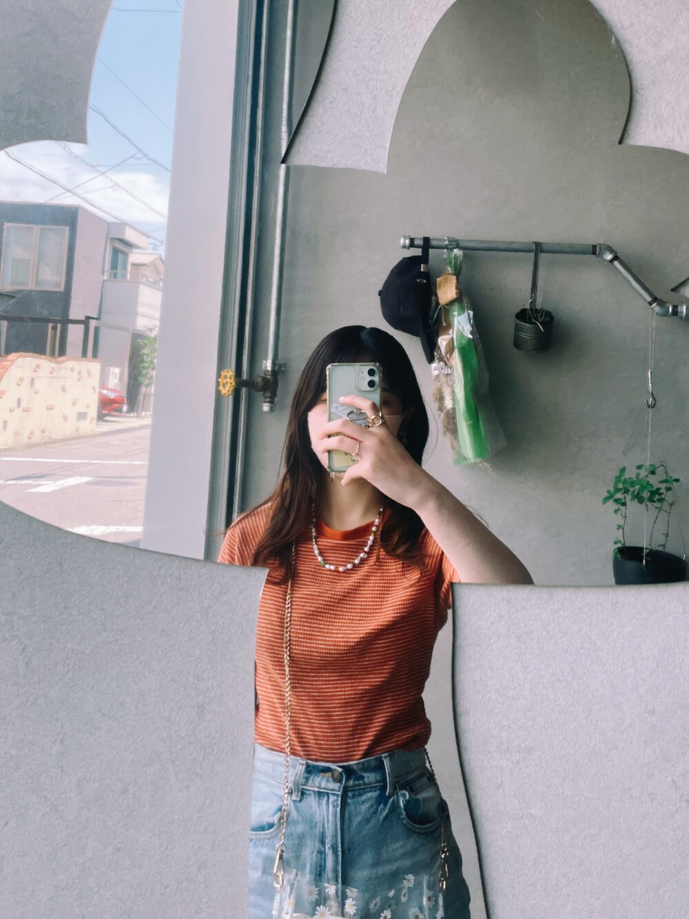 オレンジ系のTシャツ/カットソー、ブルー系のデニムパンツ、ホワイト系のショルダーバッグを着用したレディースの夏コーディネートの2枚目の写真