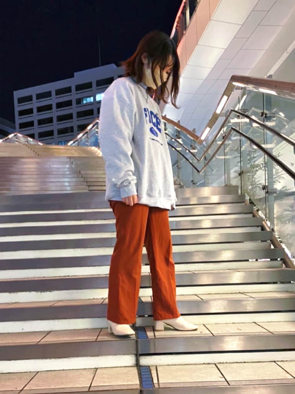 グレー系のスウェット、オレンジ系のスラックス、ホワイト系のブーツを着用したレディースの夏コーディネートの2枚目の写真