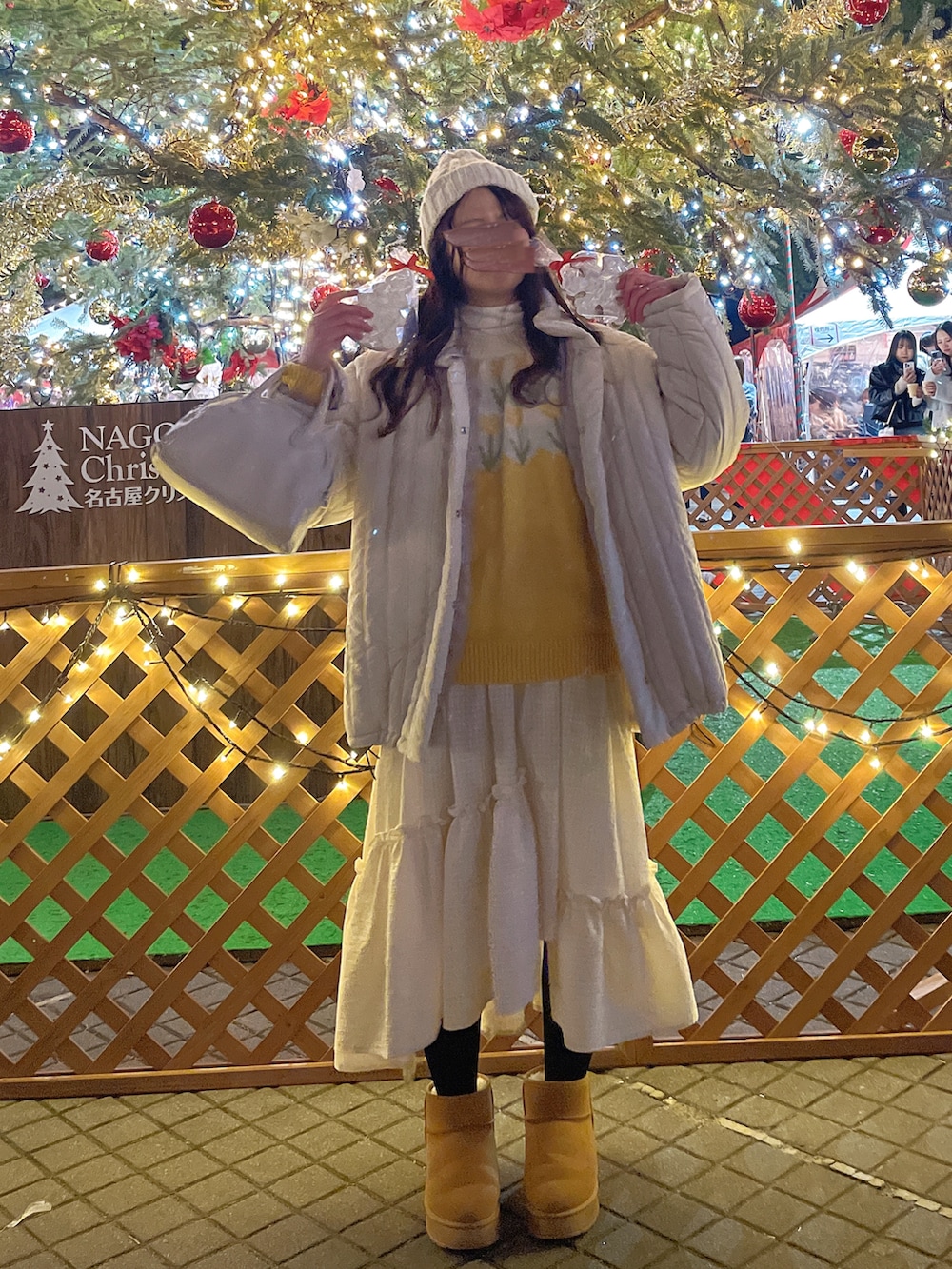 ホワイト系のダウンジャケット/コート、イエロー系のニット/セーター、ホワイト系のスカートを着用したレディースの冬コーディネートの2枚目の写真