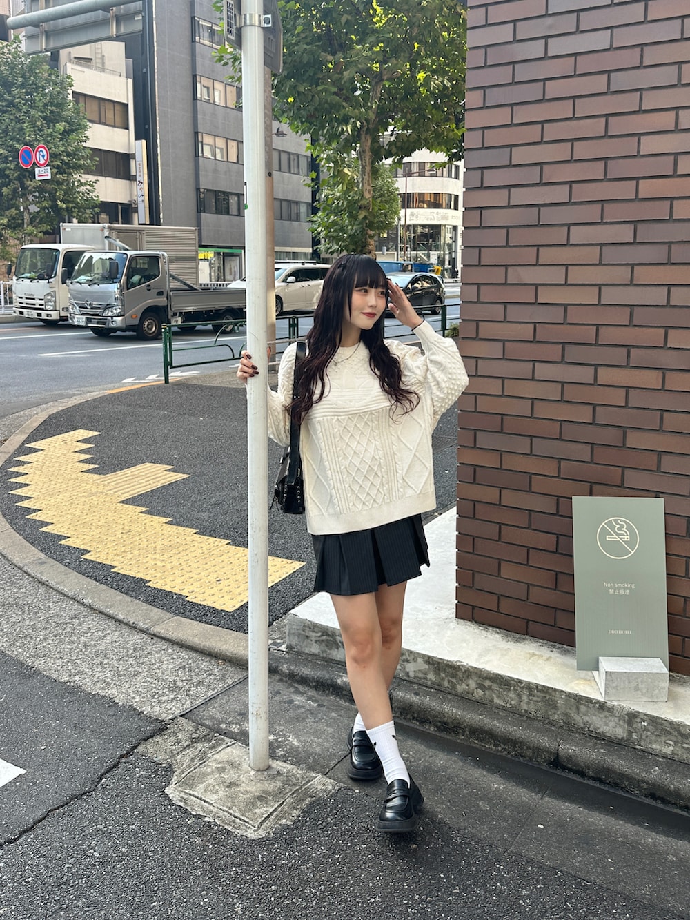 ブラック系のショルダーバッグ、ホワイト系のニット/セーター、グレー系のスカートを着用したレディースの秋コーディネートの2枚目の写真