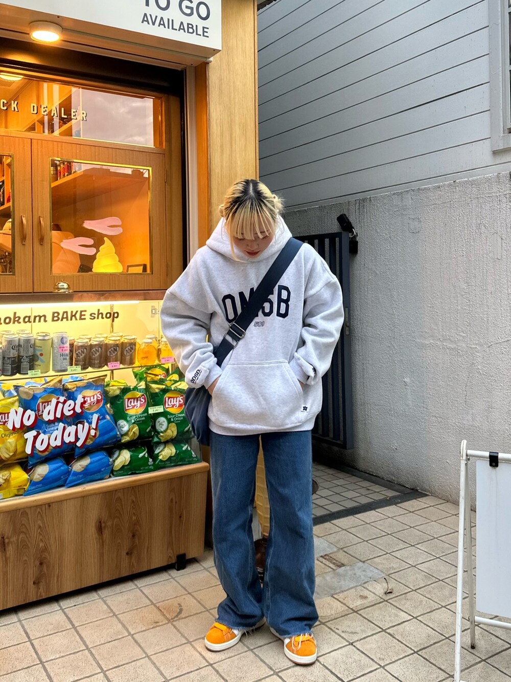 イエロー系のスニーカー、ブルー系のショルダーバッグを着用したレディースの春コーディネートの3枚目の写真