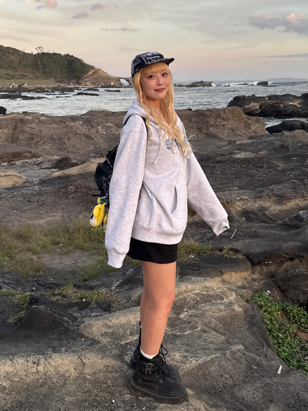 グレー系のパーカー、ブラック系のブーツ、ブラック系のキャップを着用したレディースの秋コーディネートの2枚目の写真