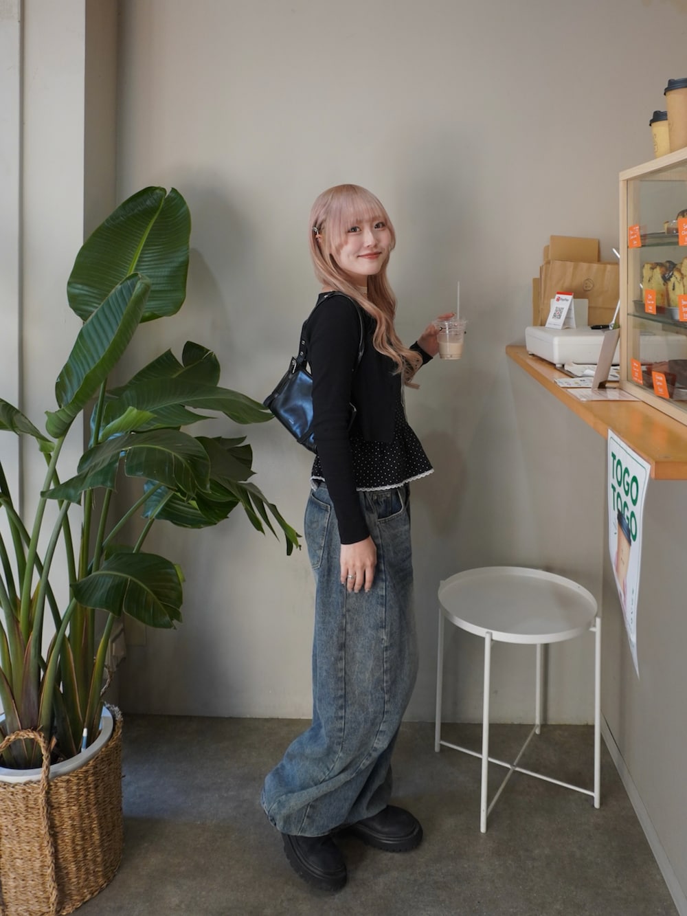 ブラック系のアンサンブル、ブラック系のブーツ、ブルー系のデニムパンツを着用したレディースの春コーディネートの2枚目の写真