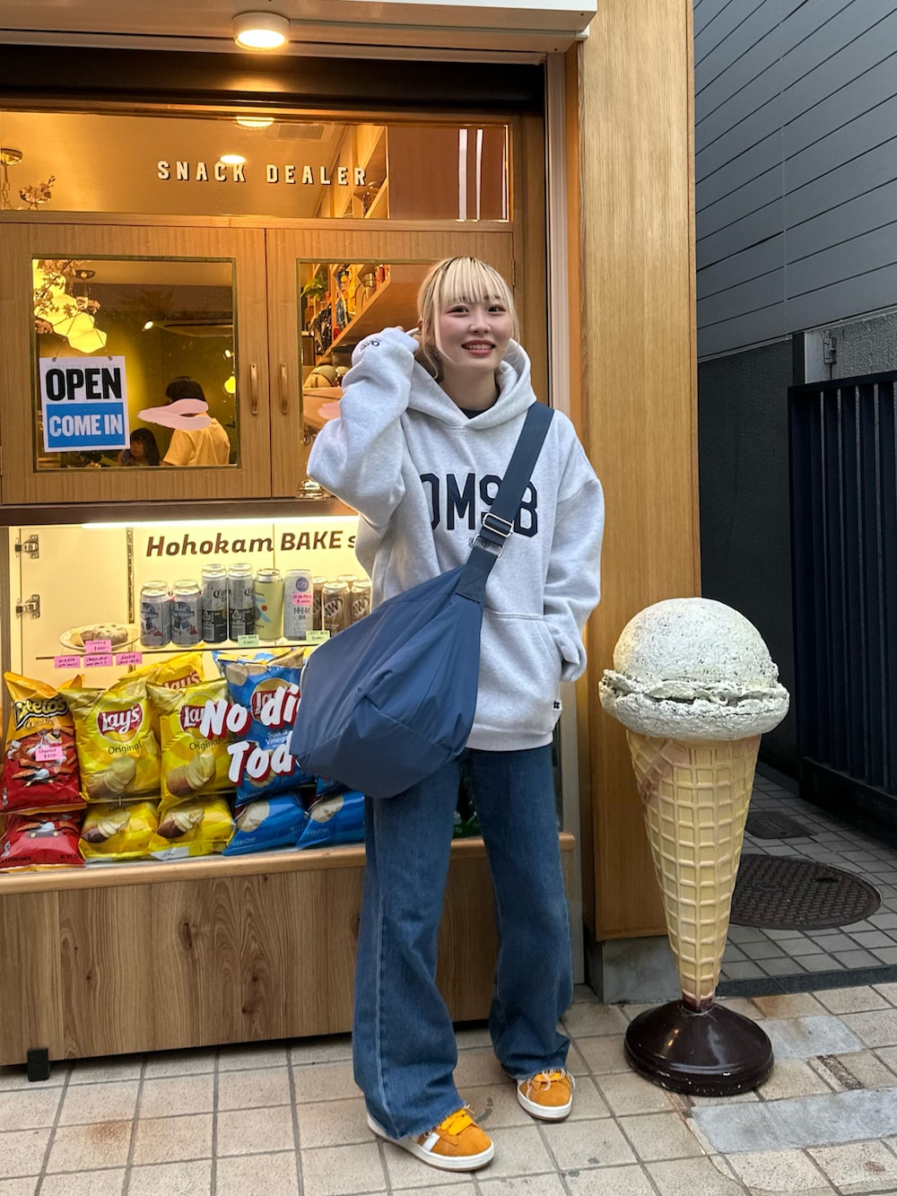 イエロー系のスニーカー、ブルー系のショルダーバッグを着用したレディースの春コーディネートの4枚目の写真