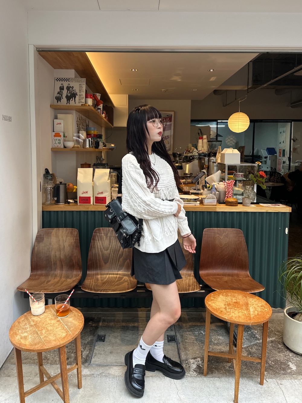 ブラック系のショルダーバッグ、ホワイト系のニット/セーター、グレー系のスカートを着用したレディースの秋コーディネートの3枚目の写真