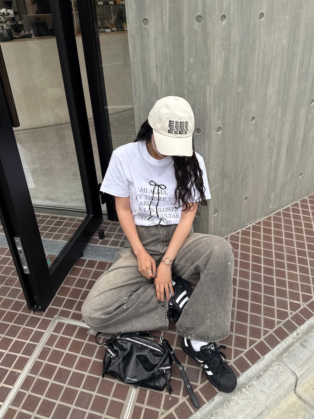 グレー系のデニムパンツ、ブラック系のスニーカー、ホワイト系のTシャツ/カットソーを着用したレディースの春コーディネートの2枚目の写真