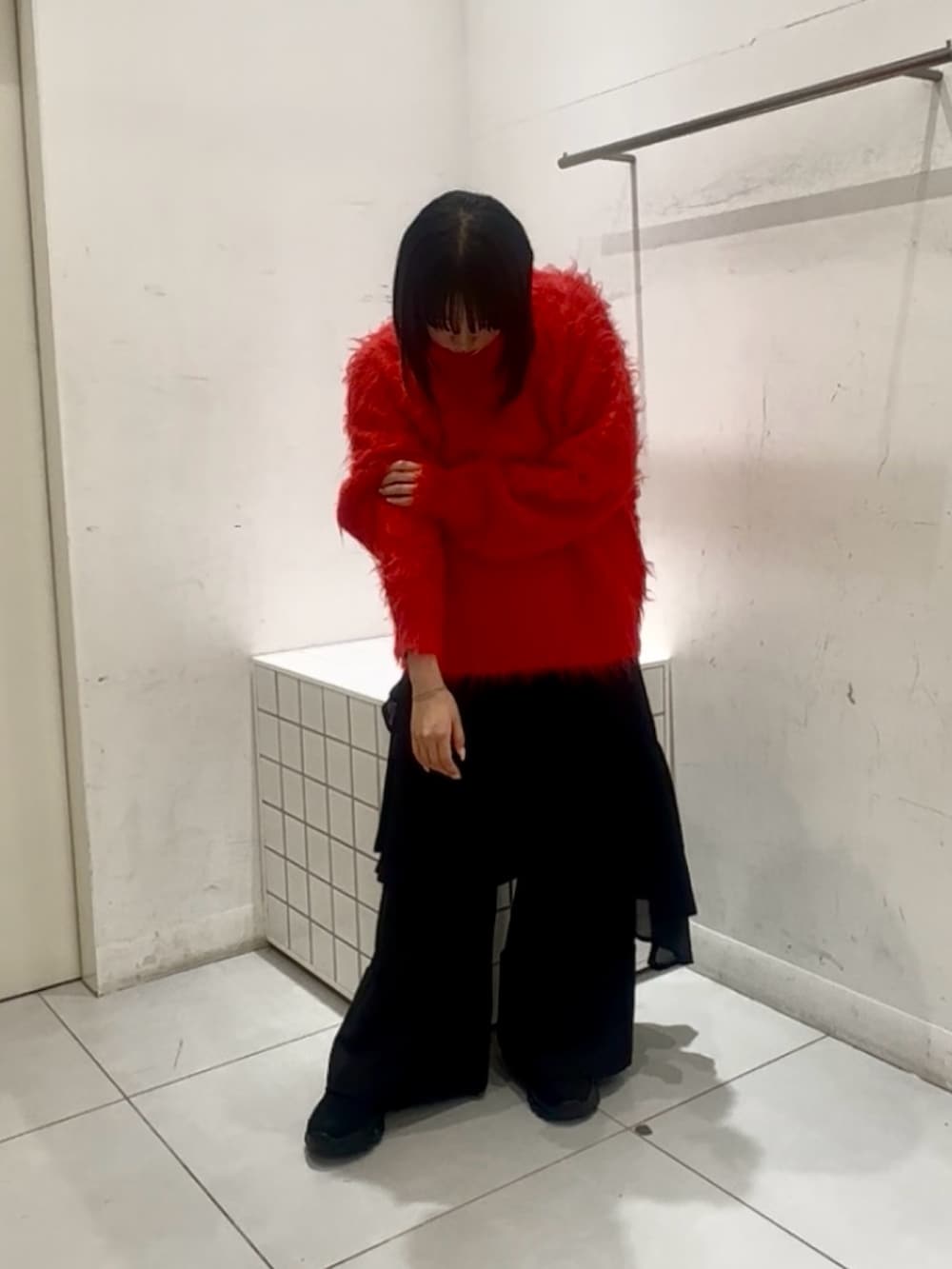 レッド系のニット/セーター、ブラック系のローファー、ブラック系のスラックスを着用したレディースの秋コーディネートの2枚目の写真