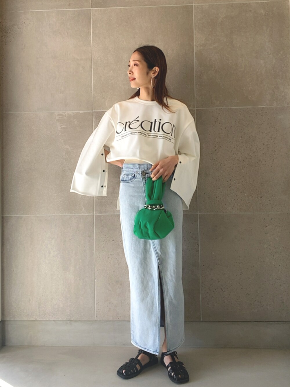 ブルー系のデニムスカート、ブラック系のサンダル、グリーン系のハンドバッグを着用したレディースの春コーディネートの2枚目の写真