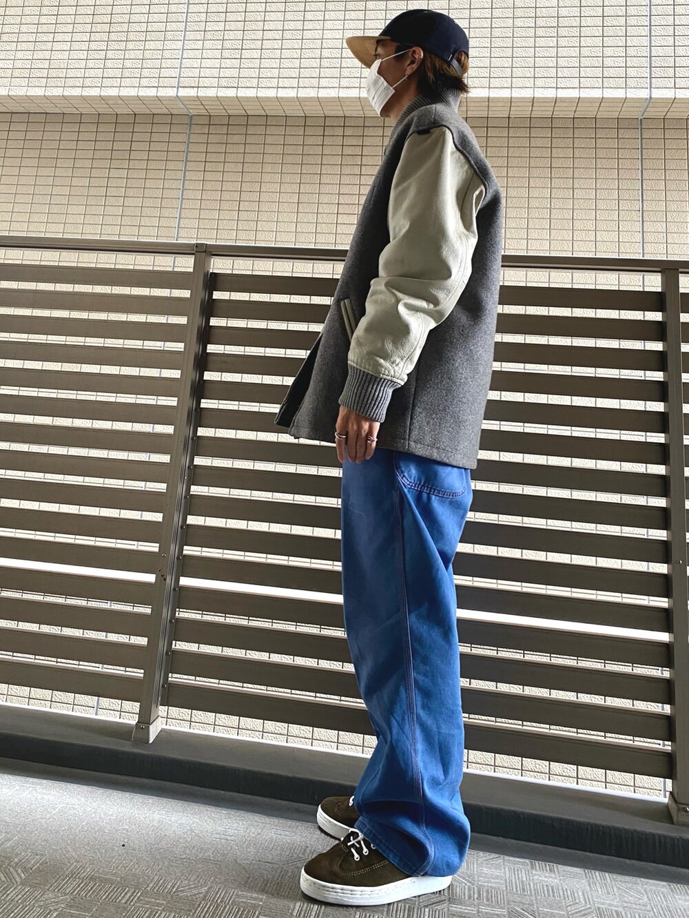 グレー系のスタジャン、ブラック系のスウェット、ブルー系のデニムパンツを着用したメンズの春コーディネートの3枚目の写真