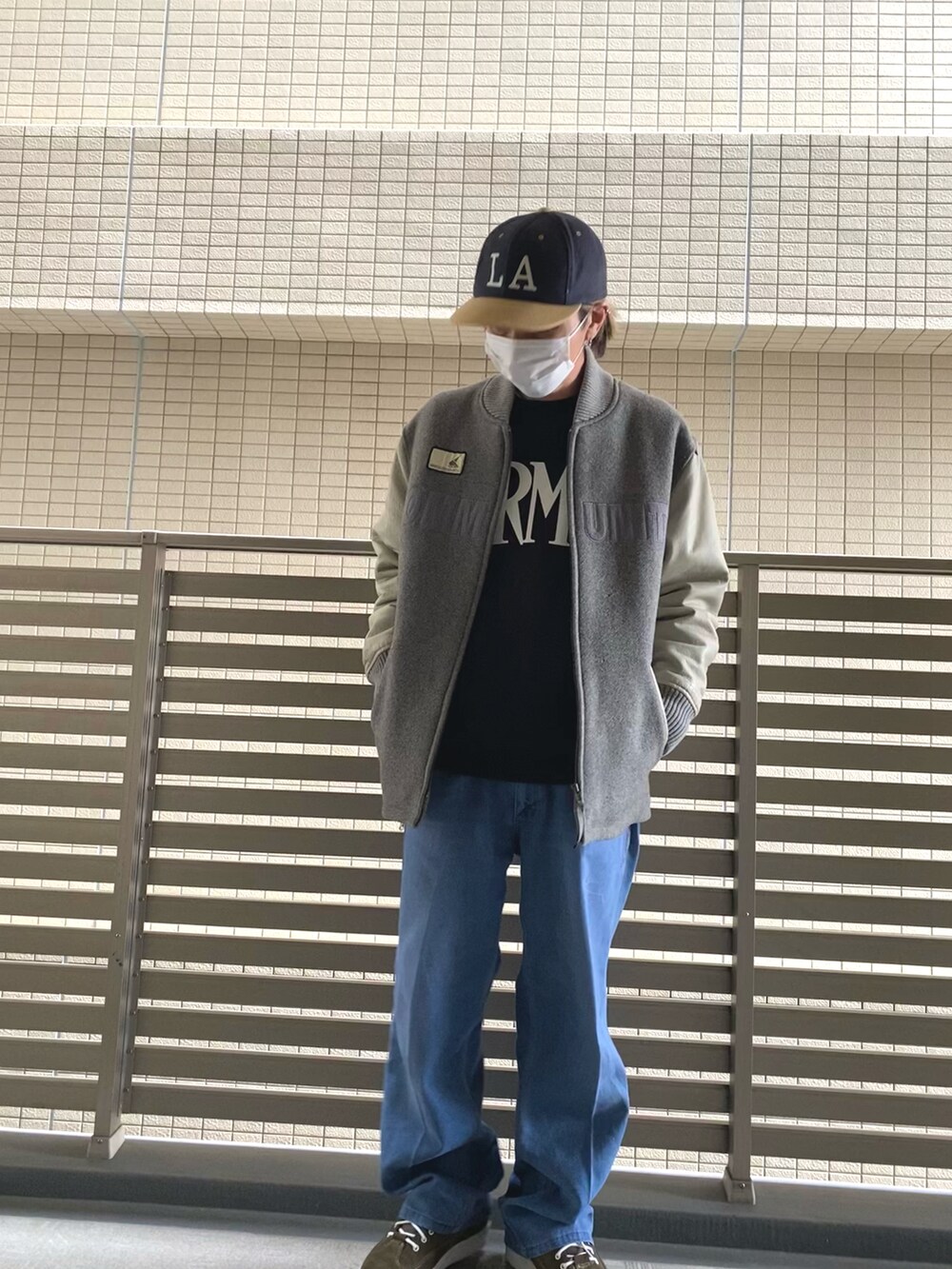 グレー系のスタジャン、ブラック系のスウェット、ブルー系のデニムパンツを着用したメンズの春コーディネートの2枚目の写真