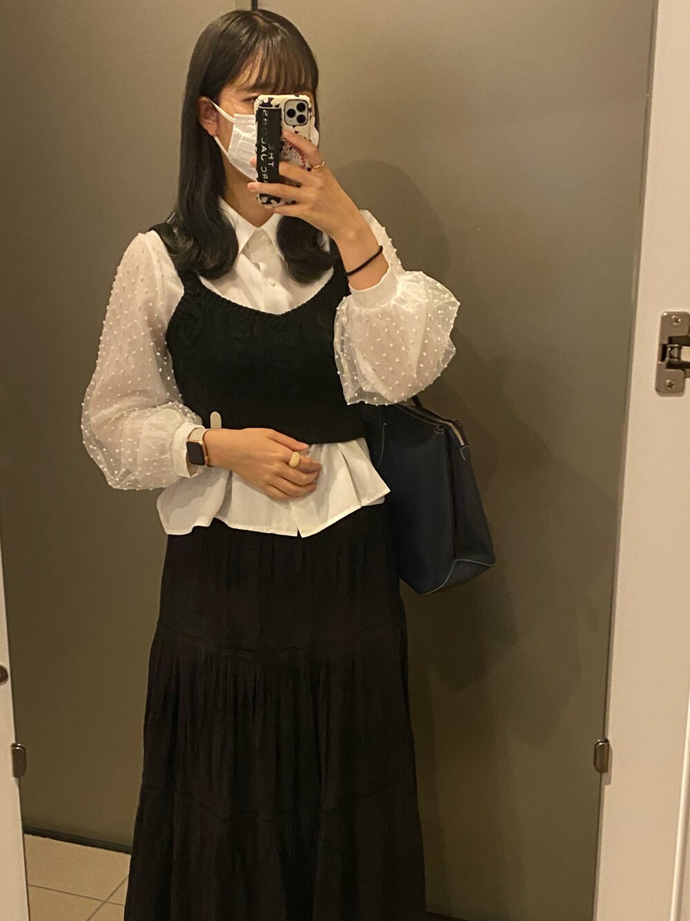 ブラック系のスカート、ホワイト系のスニーカーを着用したレディースの春コーディネートの2枚目の写真