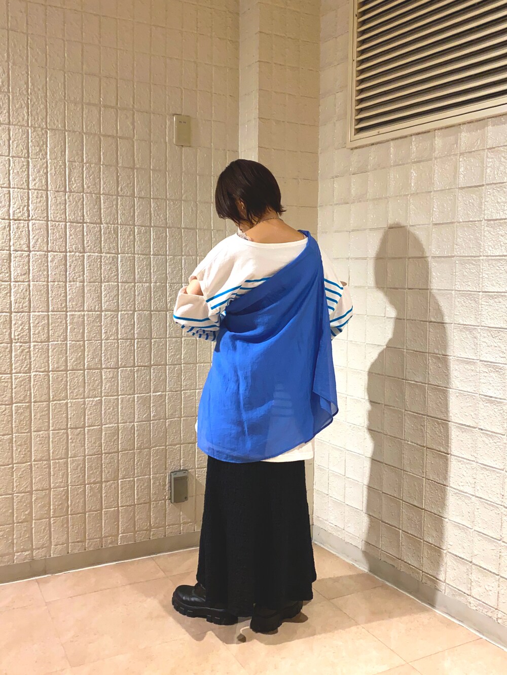 ブルー系のシャツ/ブラウス、ホワイト系のTシャツ/カットソー、ブラック系のスカートを着用したレディースの春コーディネートの2枚目の写真