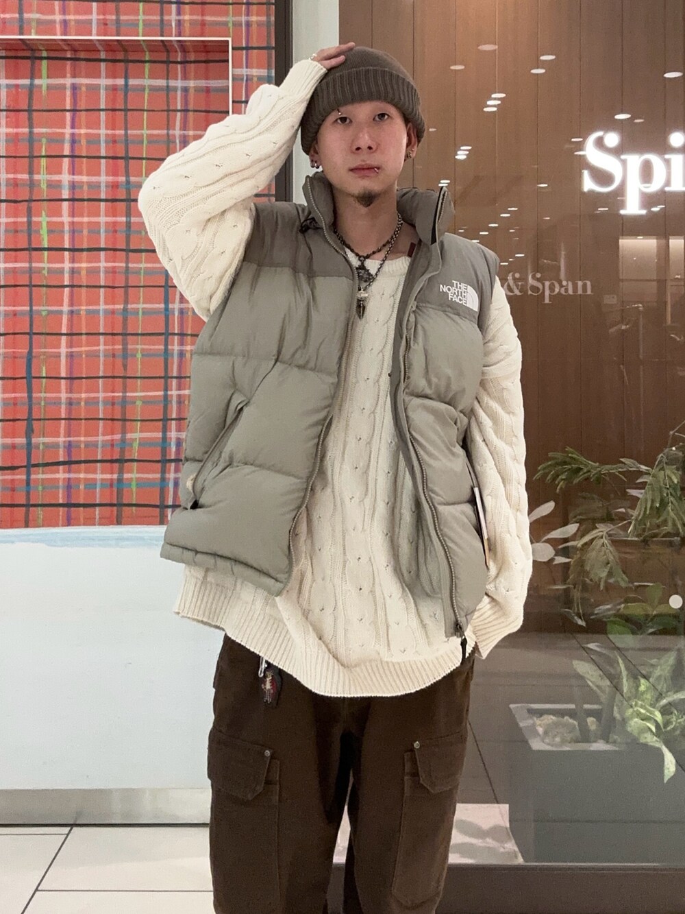 グレー系のダウンベスト、グレー系のニットキャップ/ビーニーを着用したメンズの冬コーディネートの4枚目の写真