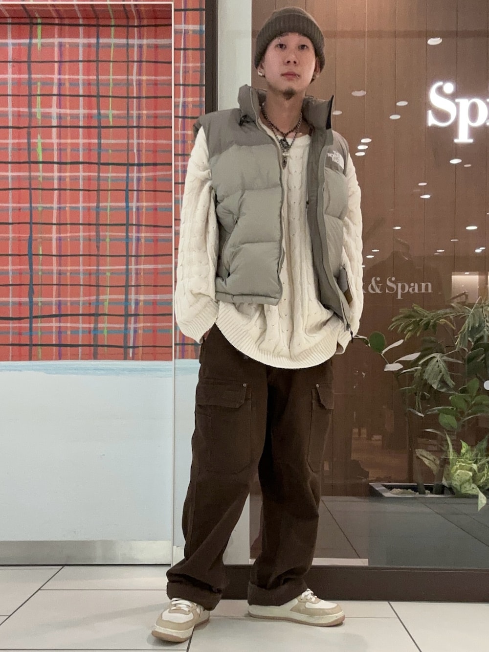 グレー系のダウンベスト、グレー系のニットキャップ/ビーニーを着用したメンズの冬コーディネートの2枚目の写真