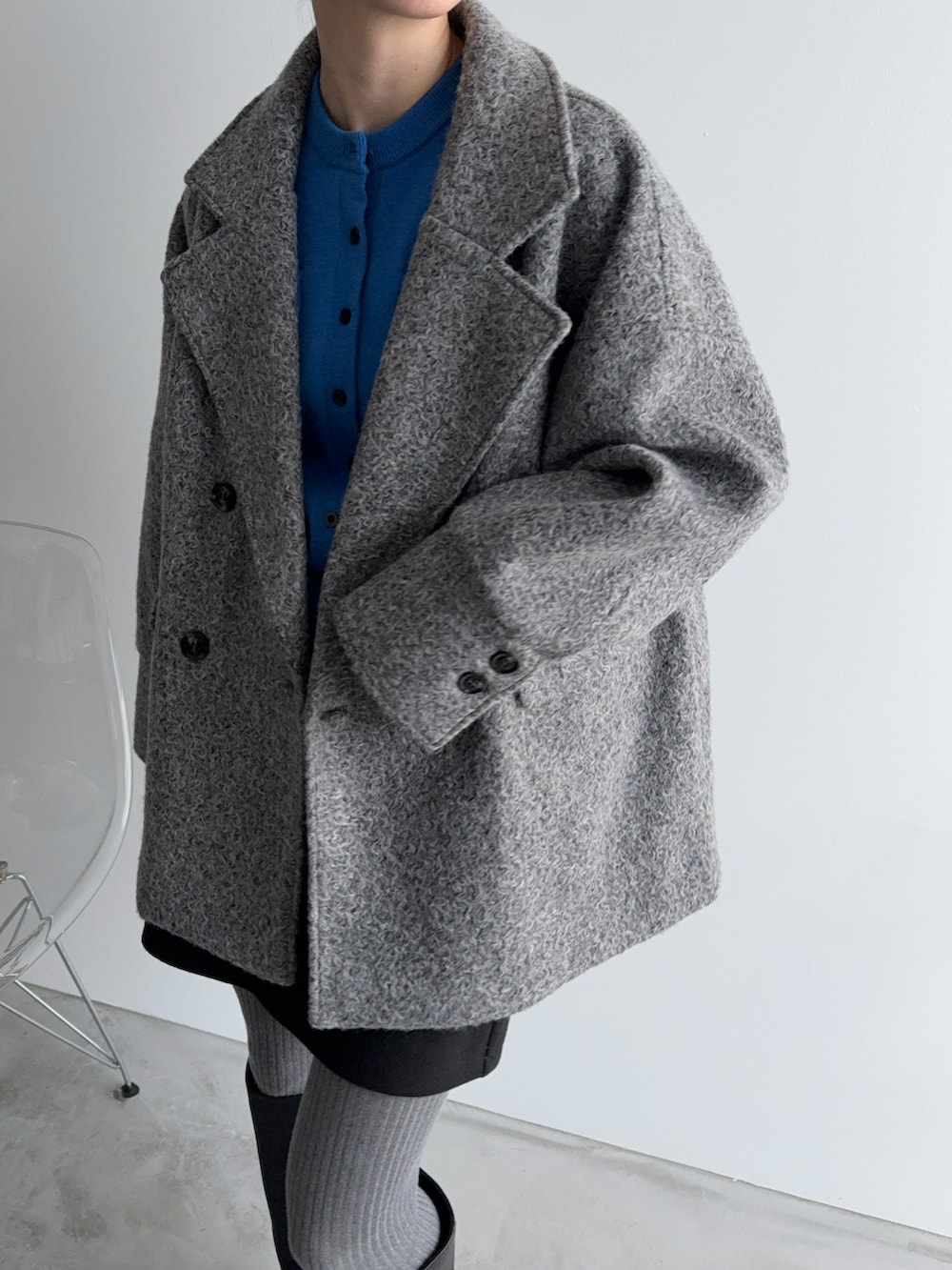 グレー系のチェスターコート、ブラック系のショルダーバッグ、ブルー系のカーディガン/ボレロを着用したレディースの冬コーディネートの2枚目の写真