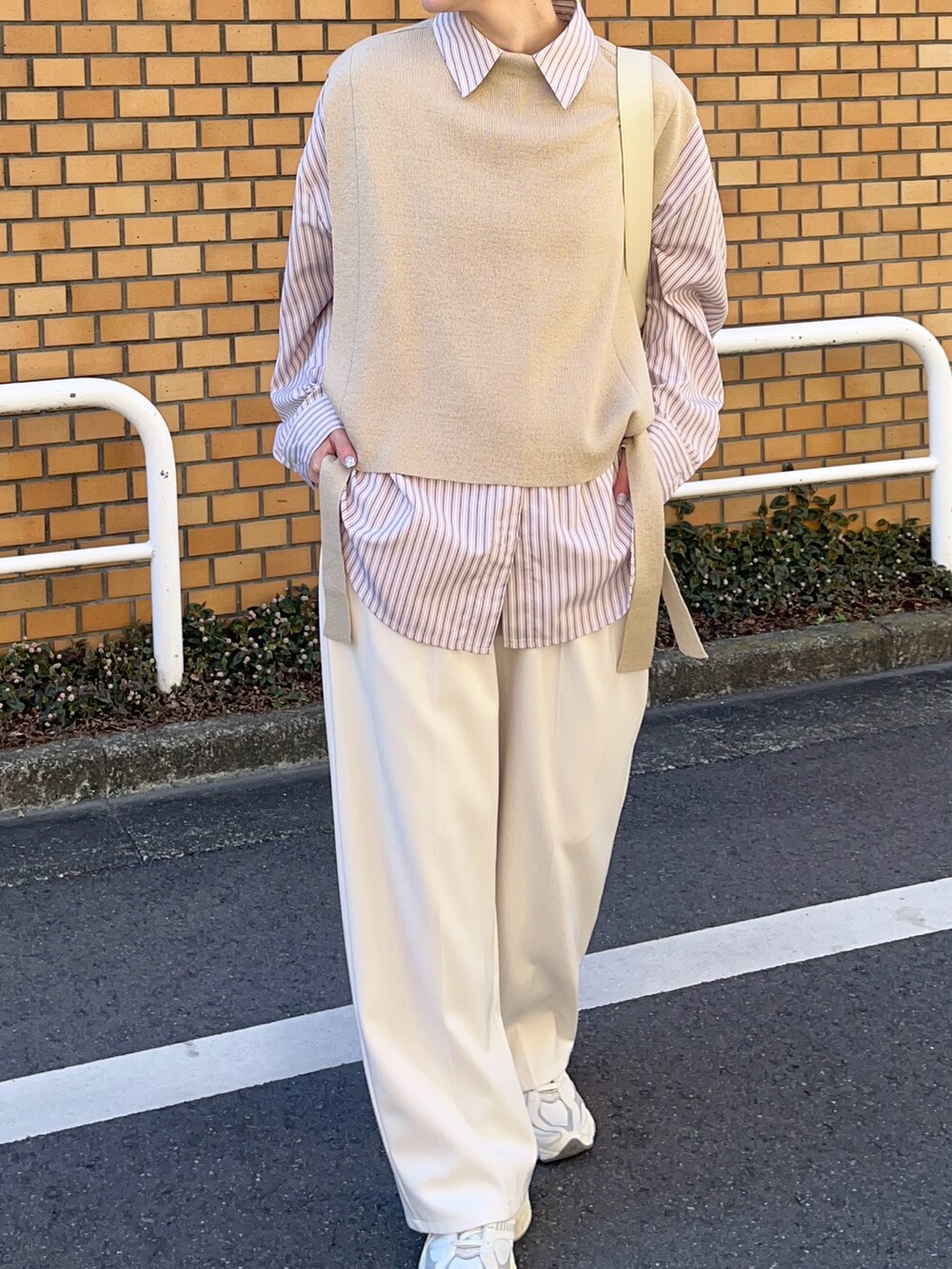 ベージュ系のベスト、ピンク系のシャツ/ブラウス、ホワイト系のショルダーバッグを着用したレディースの春コーディネートの2枚目の写真