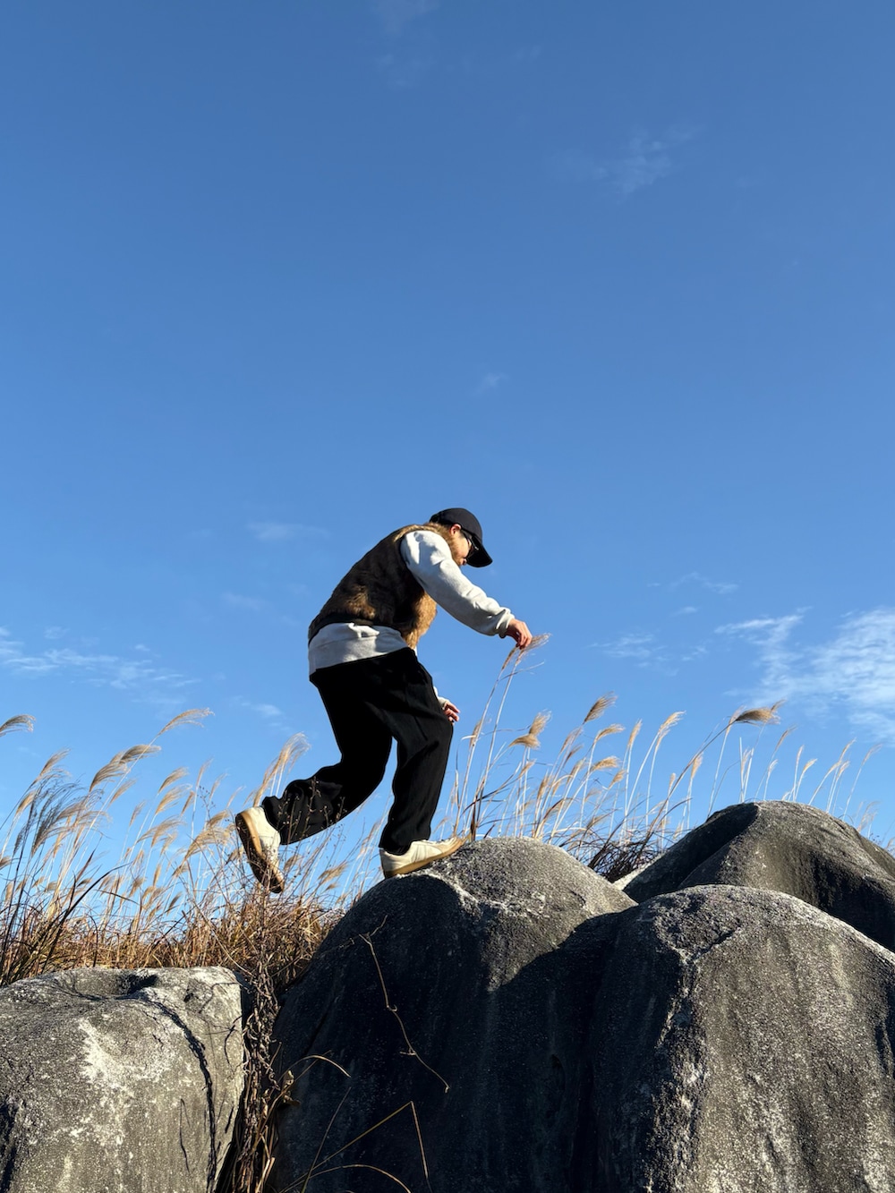 ブラウン系のベスト、ホワイト系のスウェット、ブルー系のキャップを着用したメンズの冬コーディネートの2枚目の写真