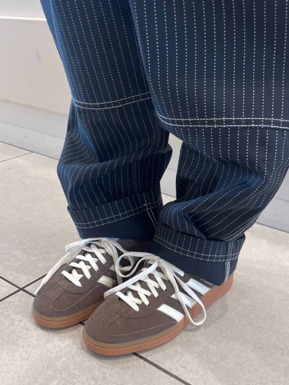 ブラック系のその他パンツ、ホワイト系のニット/セーター、ブラウン系のスニーカーを着用したレディースの春コーディネートの4枚目の写真