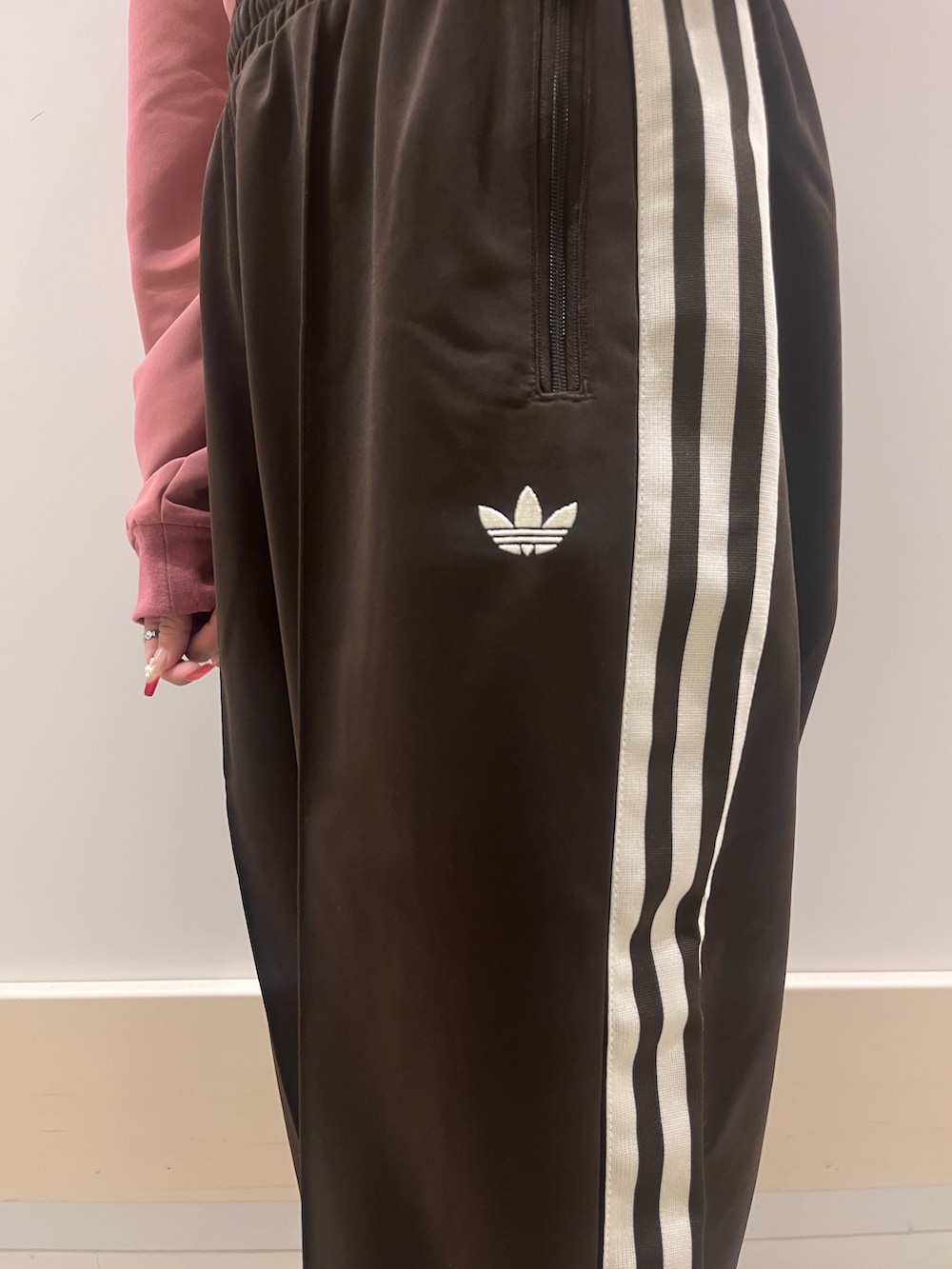 ピンク系のスニーカー、ピンク系のトップス、ブラウン系のスウェットパンツを着用したレディースの冬コーディネートの2枚目の写真