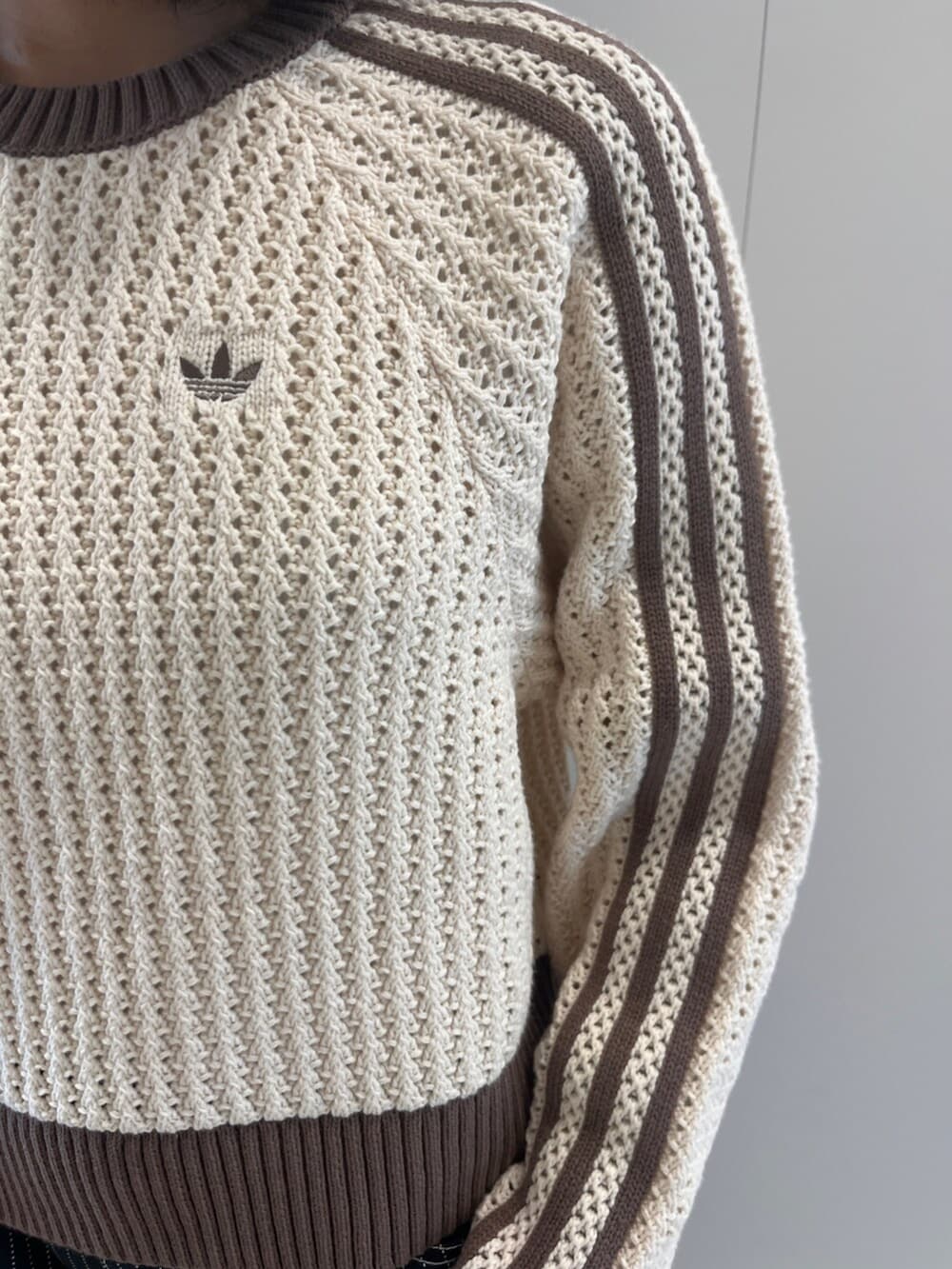 ブラック系のその他パンツ、ホワイト系のニット/セーター、ブラウン系のスニーカーを着用したレディースの春コーディネートの2枚目の写真