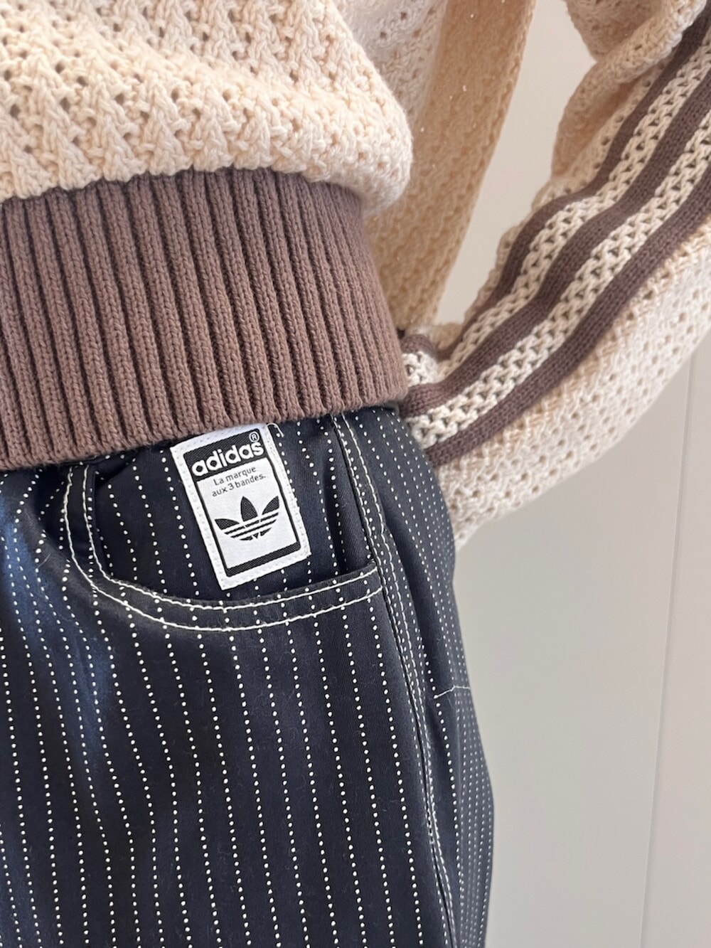 ブラック系のその他パンツ、ホワイト系のニット/セーター、ブラウン系のスニーカーを着用したレディースの春コーディネートの3枚目の写真