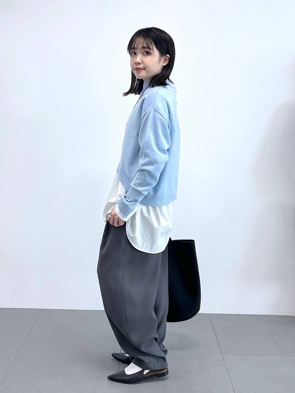 グレー系のその他パンツ、ホワイト系のシャツ/ブラウス、ブルー系のニット/セーターを着用したレディースの冬コーディネートの2枚目の写真